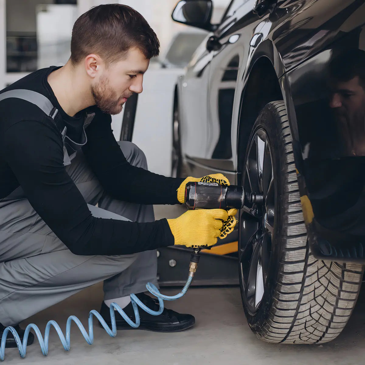 Compresor Ingco AC255016 usado con llave de impacto neumática en la rueda de un auto